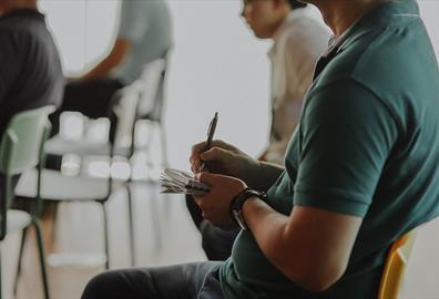 Person sitting in a chair taking notes on paper