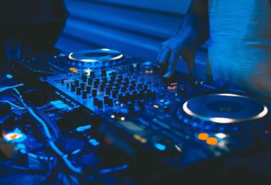 DJ and mixing decks in a blue light