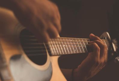 Person playing acoustic guitar with a capo