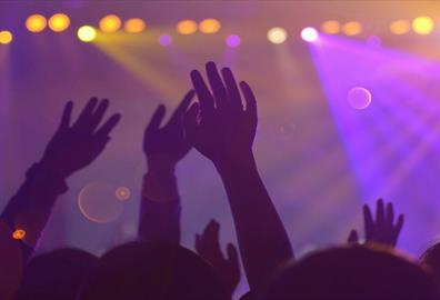 Silhouette of a crowd with raised hands at a concert