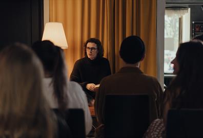 Long haired individual talking to a crowd