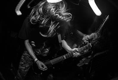 Black and white image of person with wild hair playing an electric guitar
