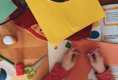 A child surrounded by bright cardboard at a craft table