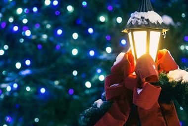 Outdoor lamp covered in snow and dressed with a red bow