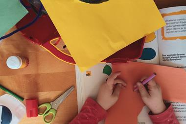 A child surrounded by bright cardboard at a craft table