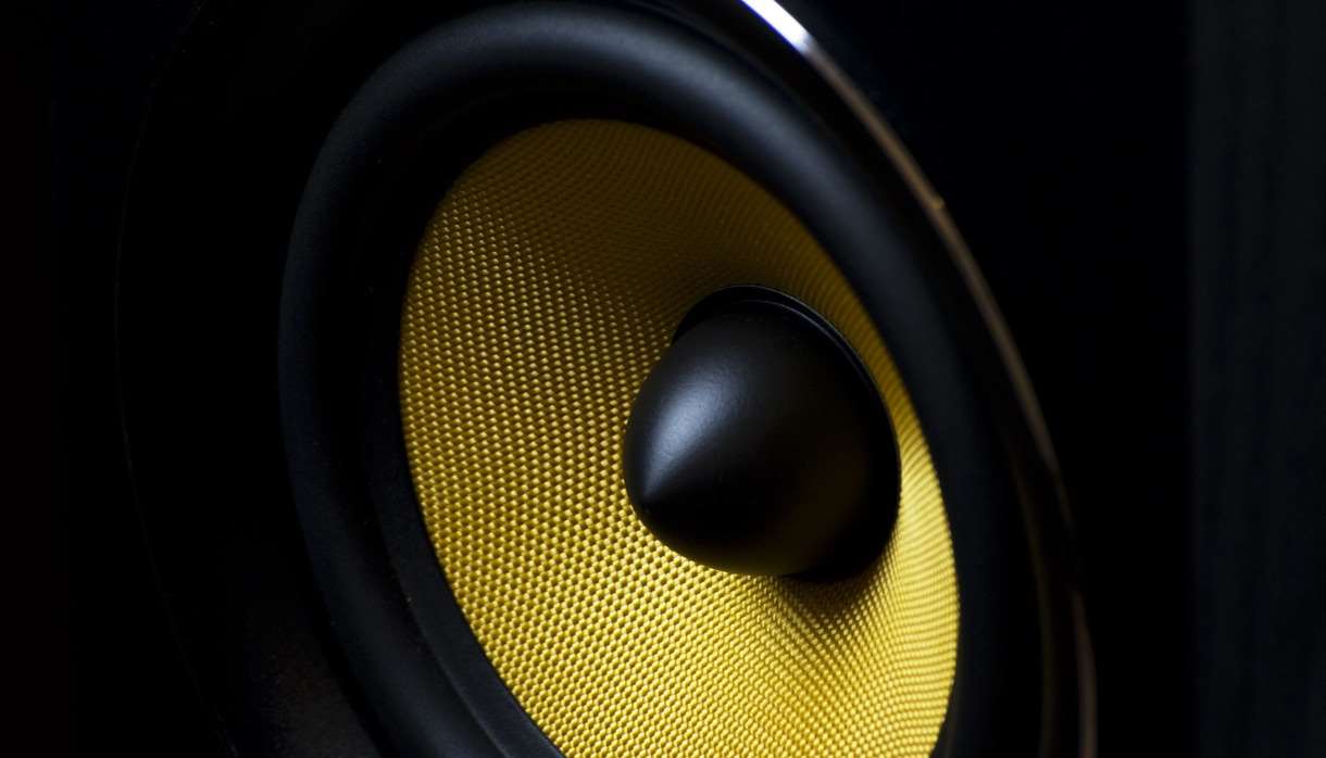 Zoomed in shot of a black speaker with bright yellow mesh