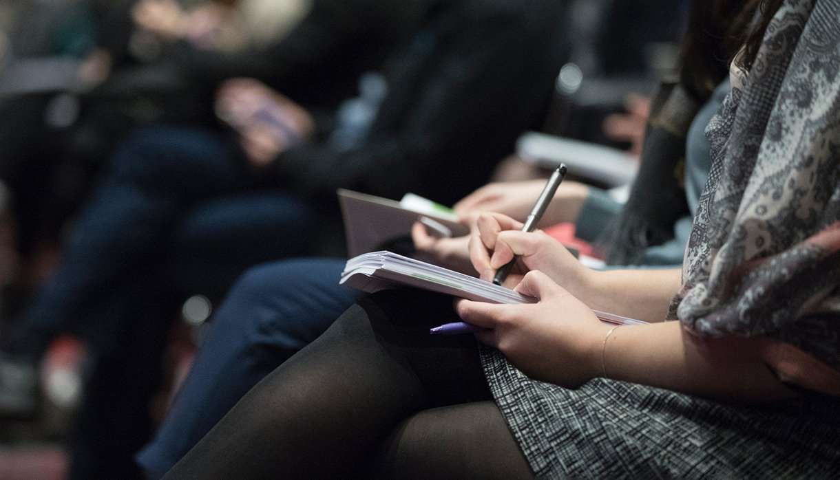 People taking notes at a lecture