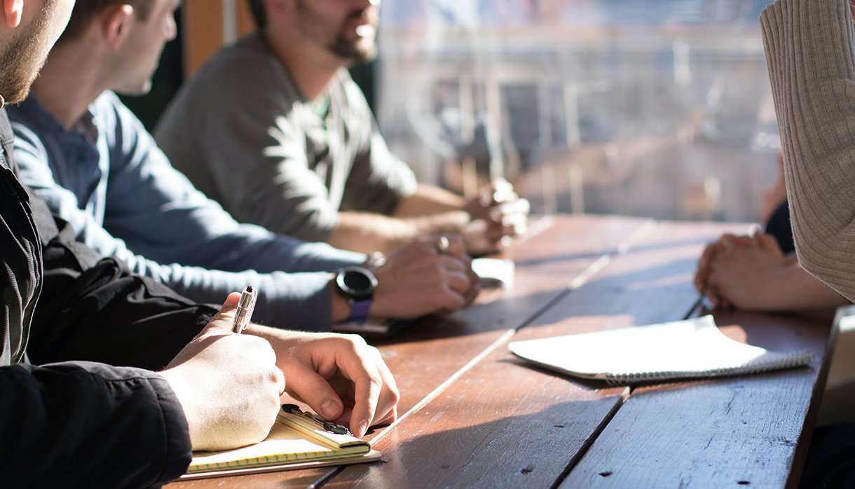 People sitting a table talking and taking notes