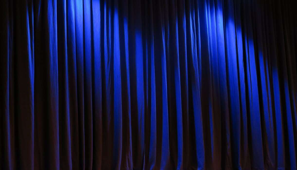 Dark blue stage curtain with light shining from spotlights above