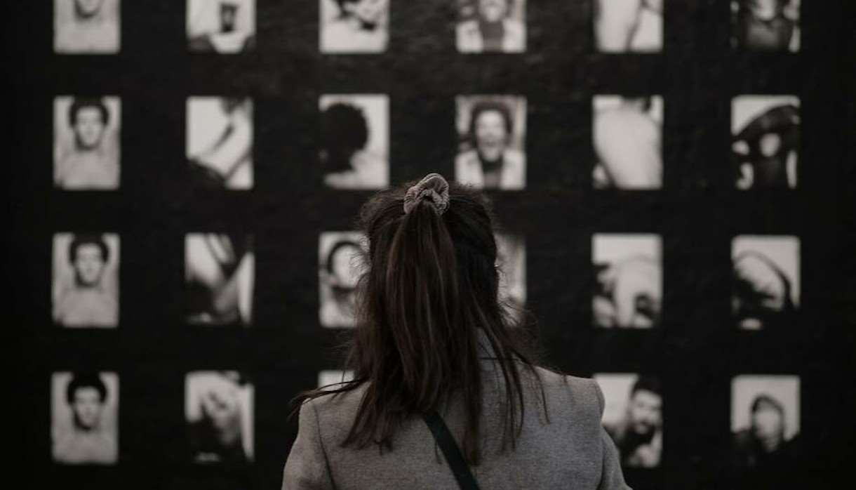 Wall of black and white photographs with person looking at them