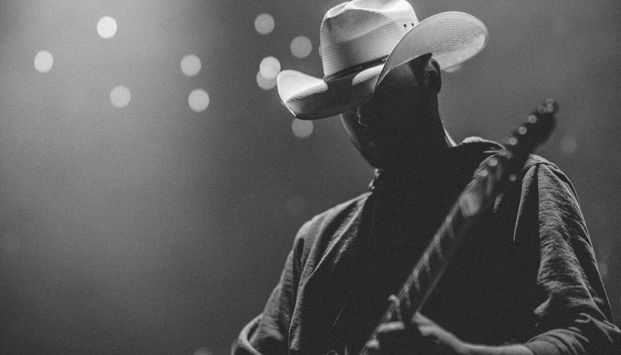 Person wearing a white cowboy hat playing on a lit stage