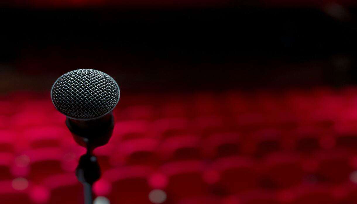 A microphone on a stage in front of red theatre seating