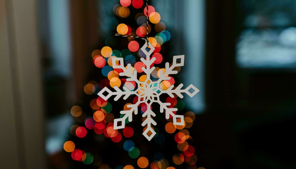White wooden snowflake decoration lit up by multi-coloured lights