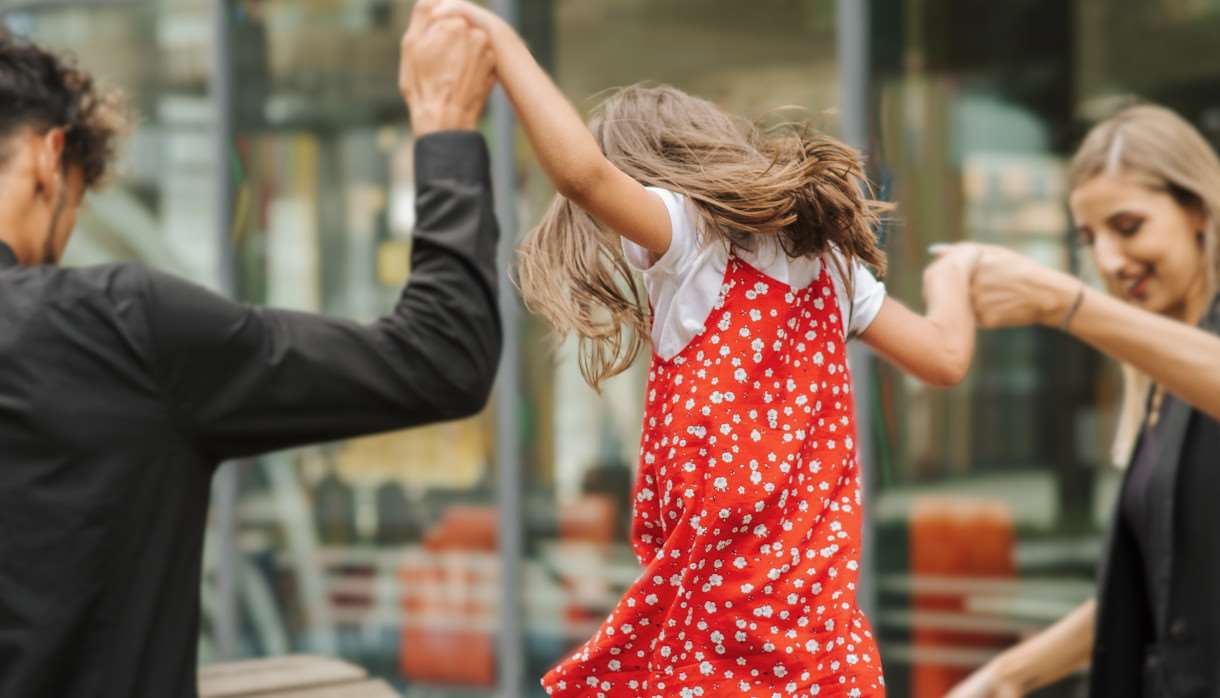 A child in a red dress with their parents