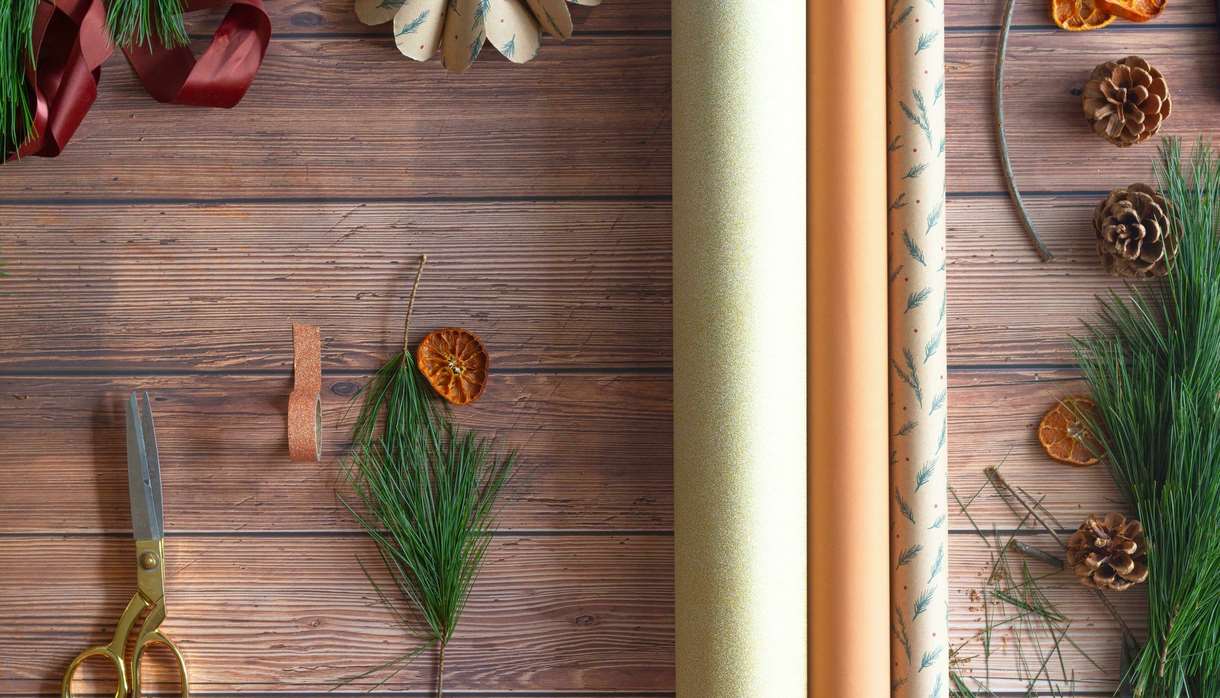 Neutral wrapping paper with Christmas tree branches and gold scissors
