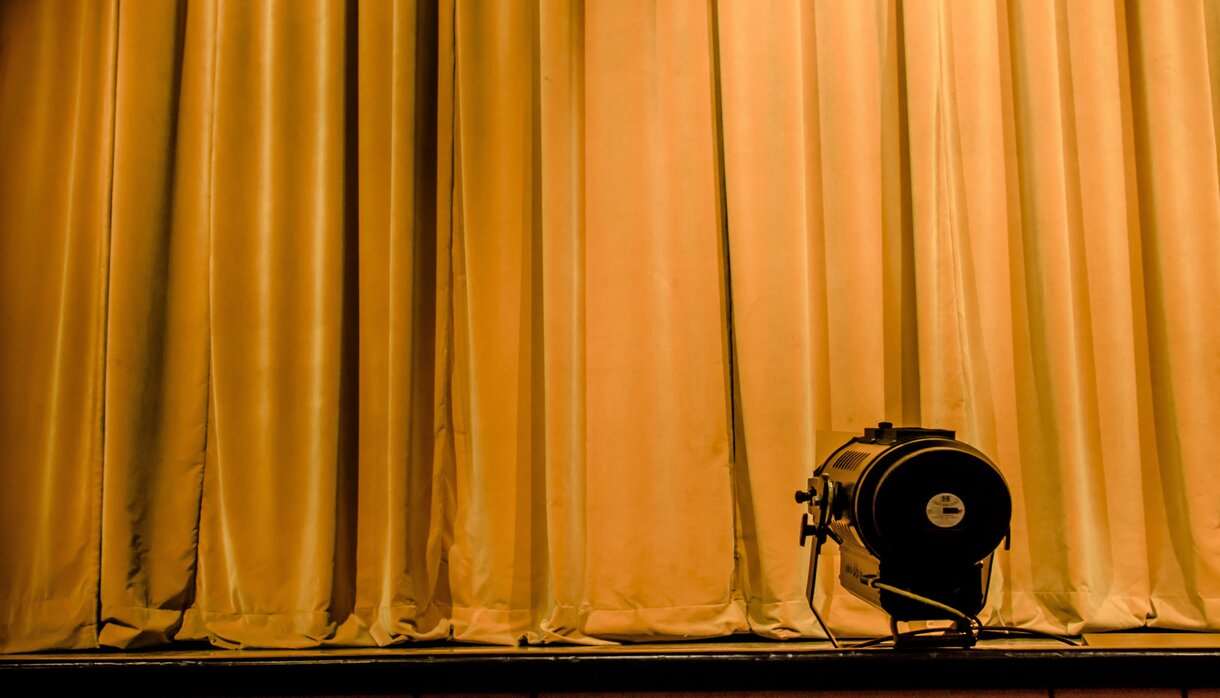Dark yellow velvet stage curtain with spotlight in foreground