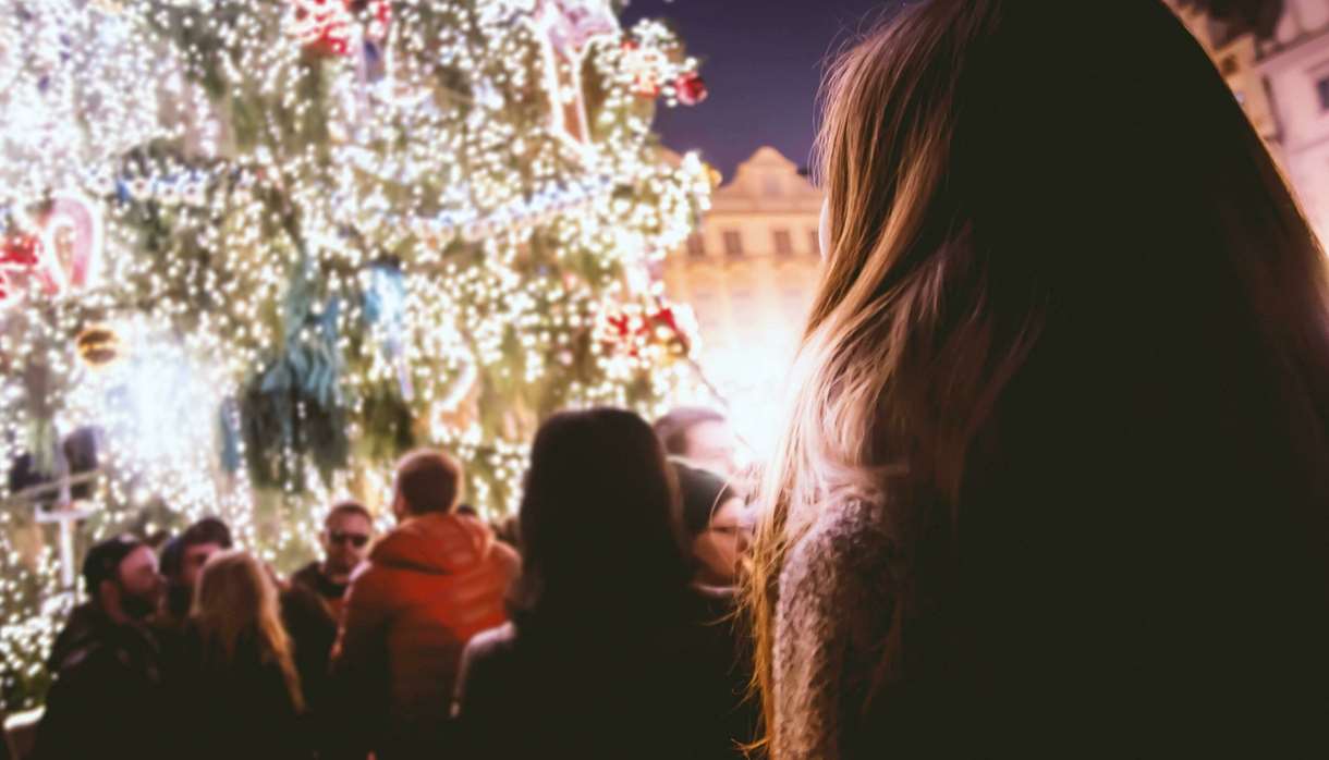 Person looking up at decorated outdoor Christmas tree