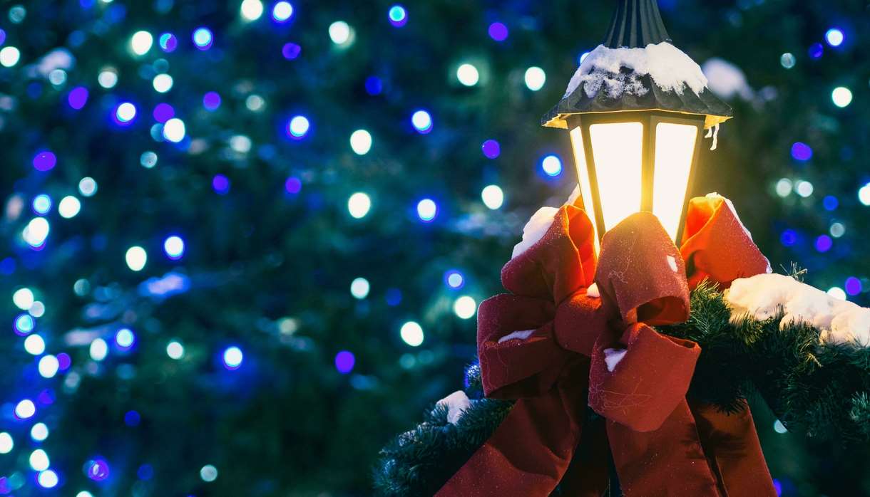 Outdoor lamp covered in snow and dressed with a red bow