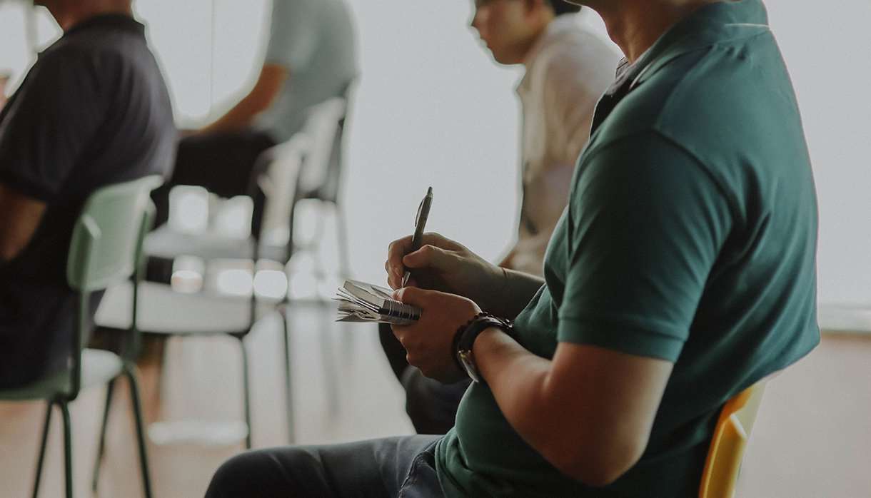 Person sitting in a chair taking notes on paper