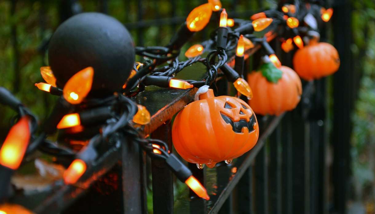 Black iron fence with orange pumpkin lights wrapped around