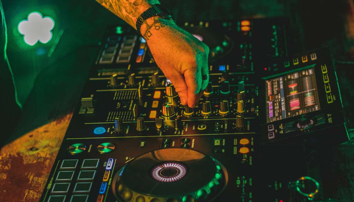 Electric mixing decks being operated by person with tattoos