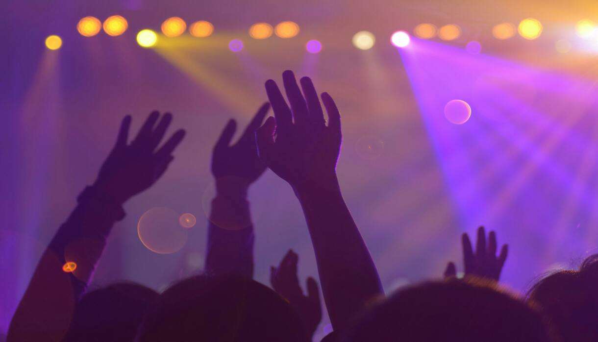 Silhouette of a crowd with raised hands at a concert