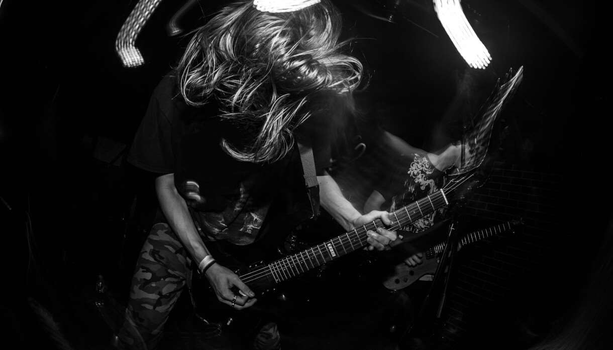 Black and white image of person with wild hair playing an electric guitar