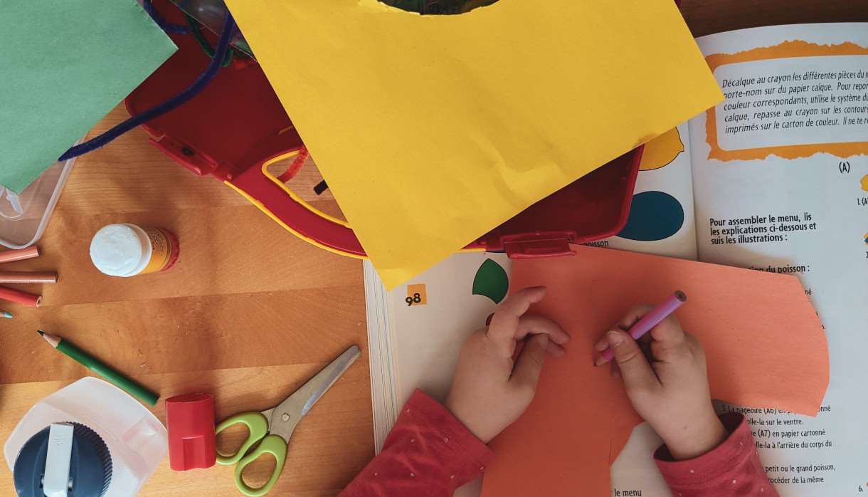 A child surrounded by bright cardboard at a craft table