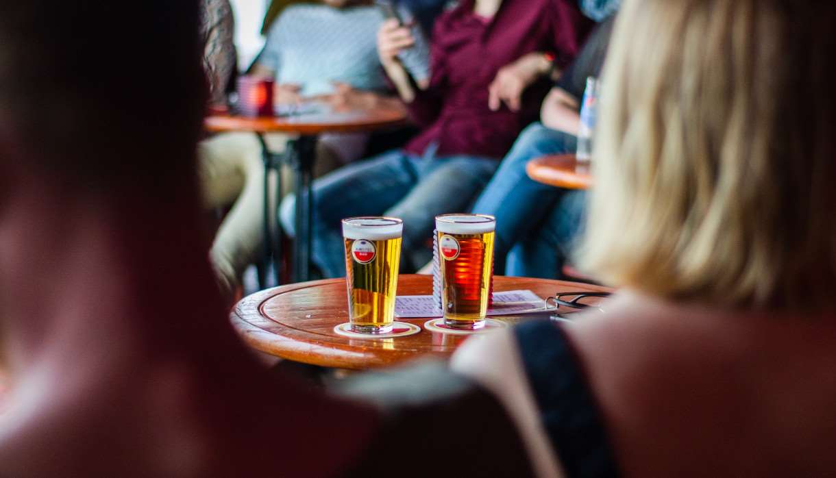 Two pints of beer on a table in a group of people