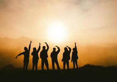 Silhouette of six people posing against a sunset