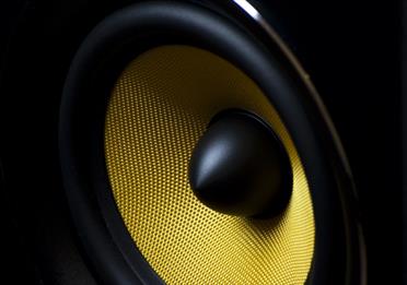 Zoomed in shot of a black speaker with bright yellow mesh