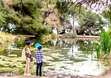 Two kids at the side of a lake in a garden
