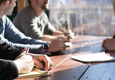 People sitting a table talking and taking notes