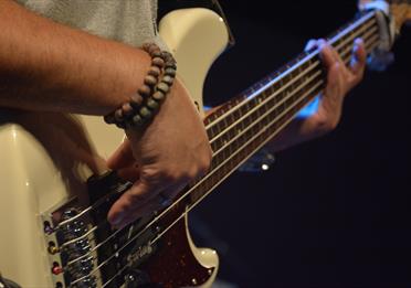 Person playing a white electric guitar