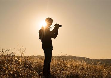 Person taking photographs in an empty field