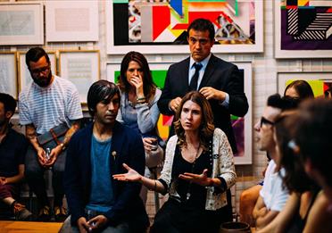 Group of people having a discussion with art on walls behind them