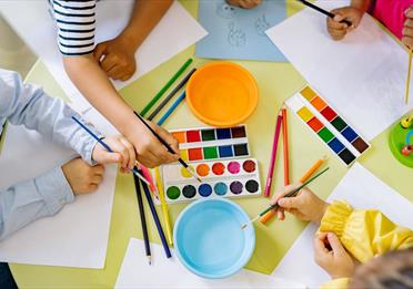 Children using pencils paint and colourful paint