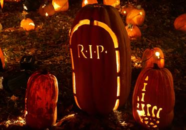 Two pumpkins carved with a skeleton hand pointing up and a tombstone