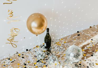 Golden confetti and disco balls with champagne bottle on the floor