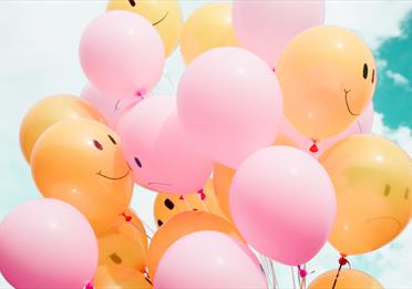 Yellow and pink balloons against a blue sky