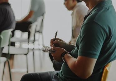 Person sitting in a chair taking notes on paper