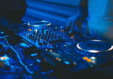 DJ and mixing decks in a blue light