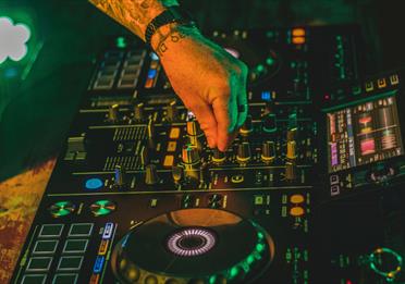 Electric mixing decks being operated by person with tattoos