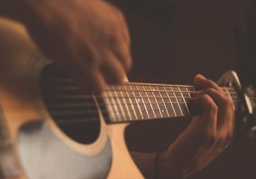 Person playing acoustic guitar with a capo