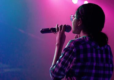 Woman onstage holding a microphone