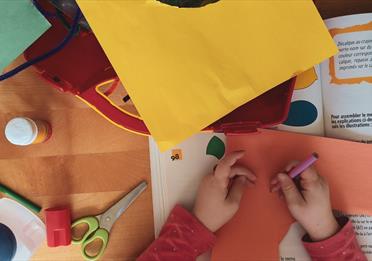 A child surrounded by bright cardboard at a craft table