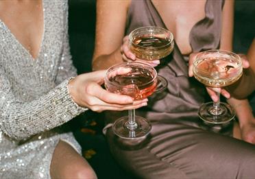 Three women in glittering dresses with shallow glasses