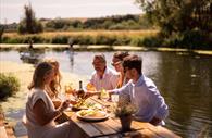 Group of friends eating beside the water.