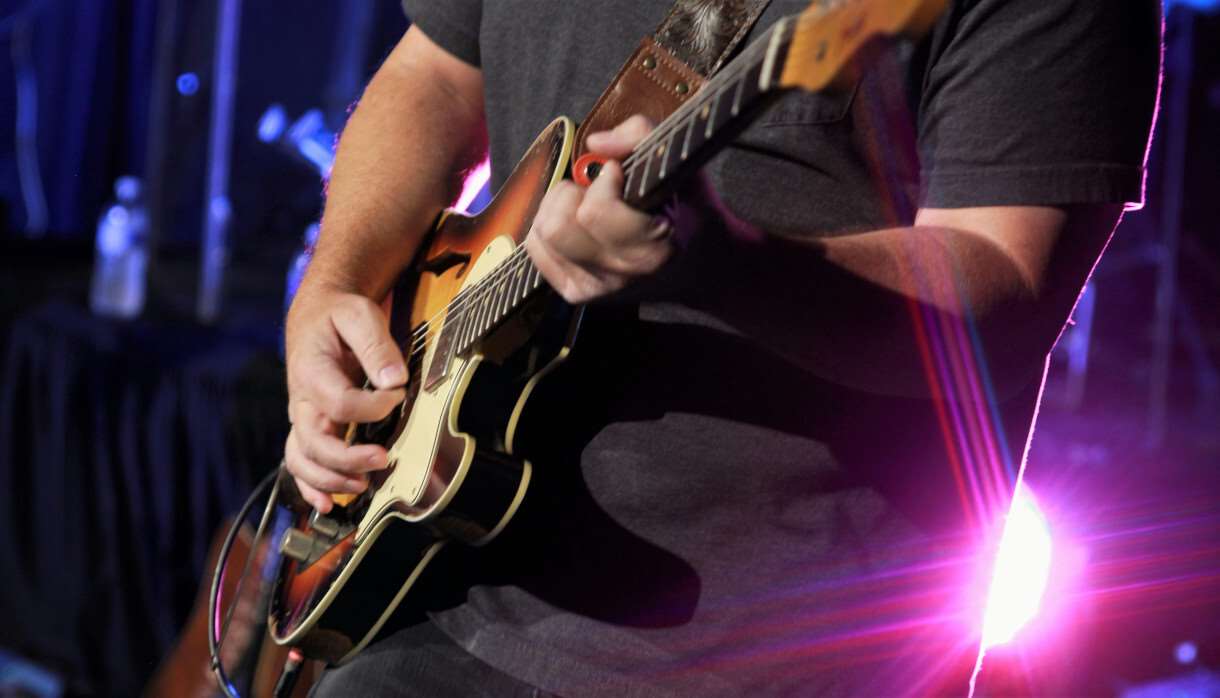 Man in black shirt playing a brown electric guitar
