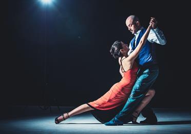 A woman in a red dress and her dance partner holding her